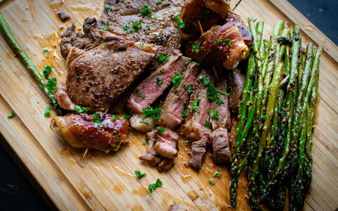 chopping board with cooked and sliced meat, and cooked asparagus