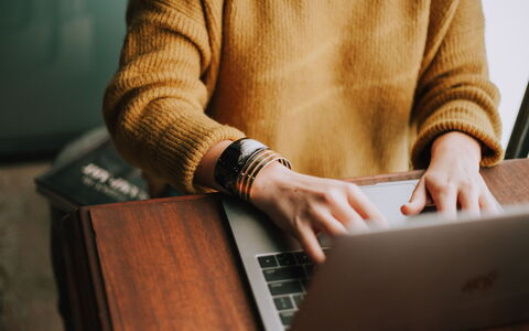 close-up of a person typing on their laptop